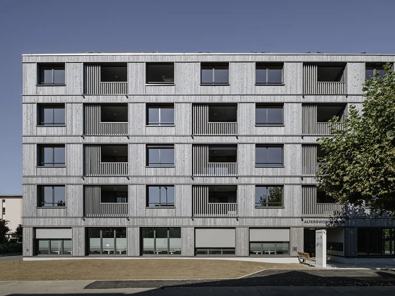 Modernes Wohngebäude mit zahlreichen Fenstern, das eine zeitgemässe Architektur präsentiert.