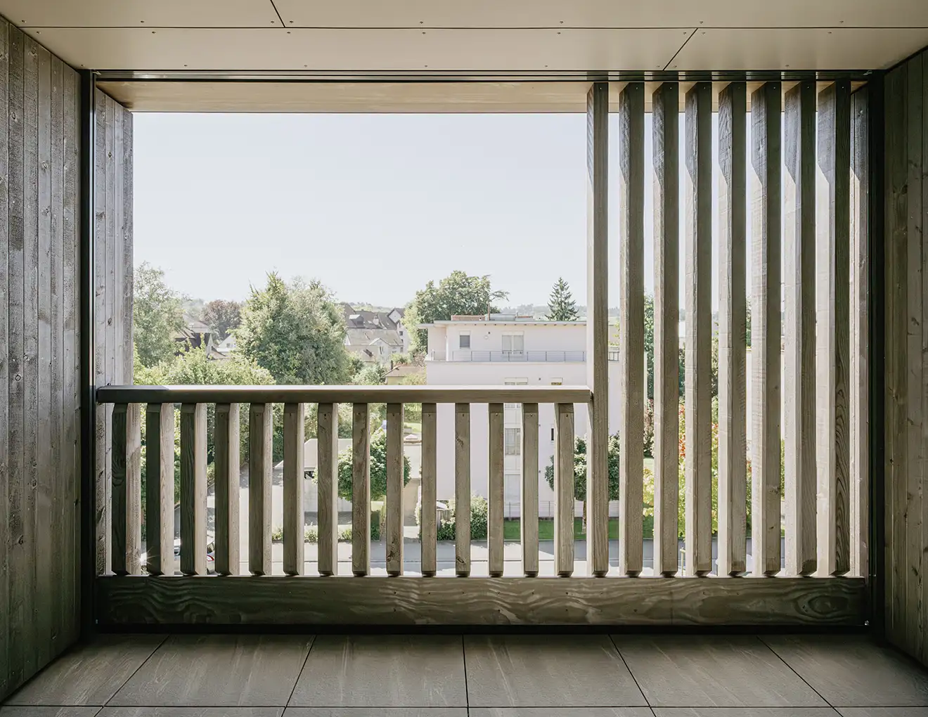 Blick auf einen Balkon mit Holzlatten, der eine einladende und natürliche Atmosphäre vermittelt.